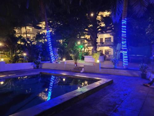 - une piscine en face d'un bâtiment la nuit dans l'établissement Comfortable 1BHK Resort Aptmt with Pool at Candolim for 4 ppl, à Goa