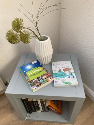 a table with two books and a vase on it at Kleines Apartment in Mönchengladbach-Neuwerk in Mönchengladbach