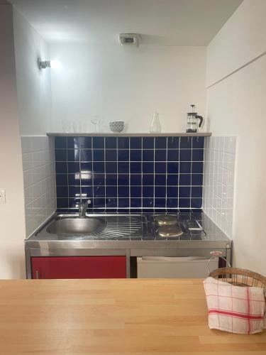 a kitchen with a sink and a blue tiled wall at Studio au coeur de Montpellier in Montpellier