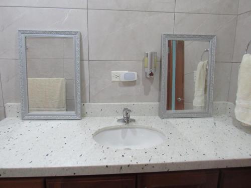 a bathroom counter with a sink and two mirrors at Casa Pacifico Panama in Las Lajas