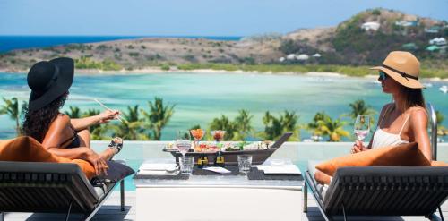 two women sitting in chairs looking at the ocean at Villa Lodge 4 Epices in Gustavia