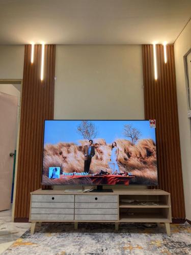 a large flat screen tv sitting on top of a cabinet at PakYa Homestay in Kampong Padang Jawa