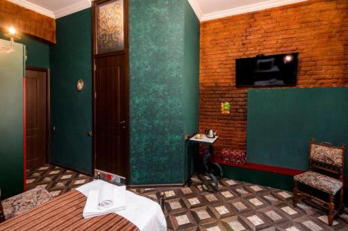 a bedroom with green walls and a bed and a chair at Vorontsoff Inn Boutique Hotel in Tbilisi City