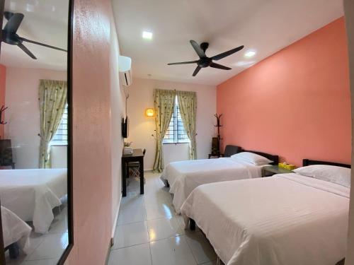 a bedroom with three beds and a ceiling fan at Besut Guesthouse in Kuala Besut