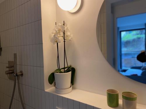 eine weiße Vase mit weißen Blumen auf einem Regal im Badezimmer in der Unterkunft Studio Heinrich 1 in Tutzing