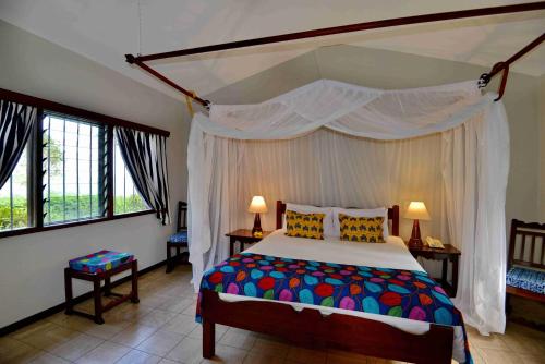 a bedroom with a large bed with a canopy at Mnarani Beach Club in Kilifi