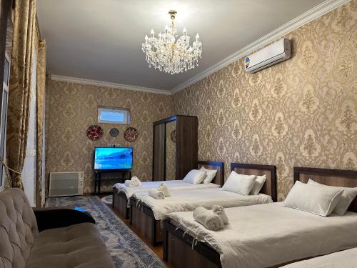 1 dormitorio con 3 camas y lámpara de araña en Guest house Chehra, en Samarkand