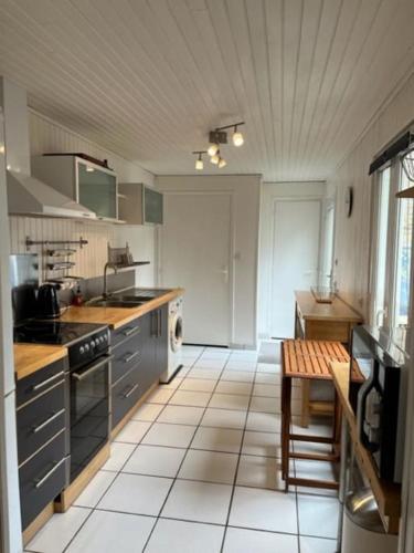 Il comprend une cuisine avec des placards gris et du carrelage blanc. dans l'établissement Gîte du Port, à Ploubazlanec