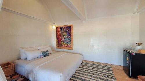 a bedroom with a white bed and a painting on the wall at Maliblues Bed & Art Gallery in Chumphon