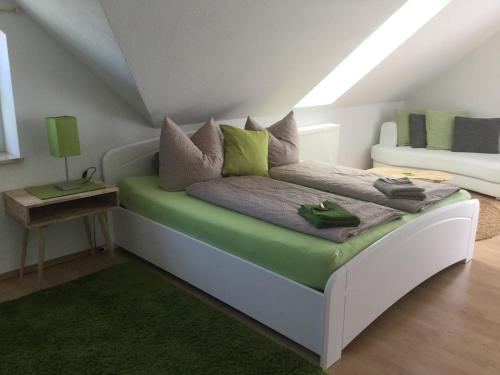 ein Schlafzimmer mit einem Bett mit grünen und grauen Kissen in der Unterkunft Ferienwohnung mit Blick auf den Kickelhahn in Ilmenau