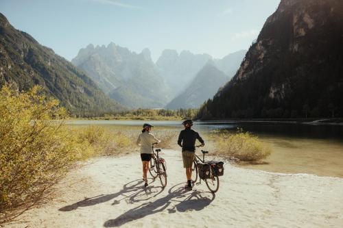 two people riding bikes on a dirt path next to a river at Dolomites Smart Holidays in Valdaora