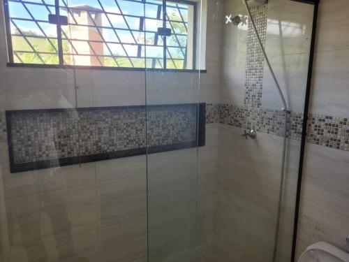 a bathroom with a glass shower with a window at Rancho Morro do Cristo - Ribeirão Claro PR in Ribeirão Claro