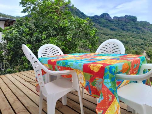 une table et des chaises sur une terrasse avec des montagnes en arrière-plan dans l'établissement Maupiti Dreams, à Te-Fare-Arii
