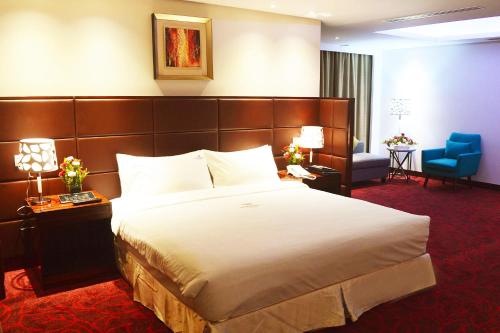 a hotel room with a large bed and a blue chair at Dhaka Regency Hotel & Resort in Dhaka