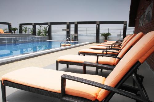 a row of lounge chairs next to a swimming pool at Dhaka Regency Hotel & Resort in Dhaka