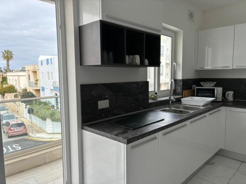 a kitchen with white cabinets and a large window at Modern Cozy & Spacious Apartments in Malta - Perfect Stay Near Saint Julians in Is-Swieqi