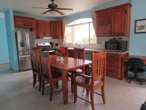a kitchen with a wooden table with chairs and a refrigerator at Casa Pacifico Panama in Las Lajas