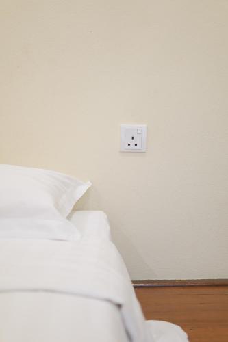 a white switch on a wall next to a bed at Dream & Wander Homestay in Ipoh