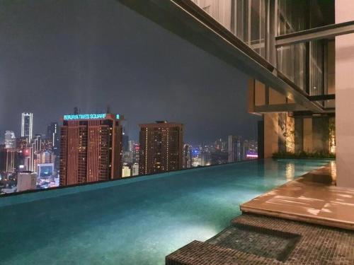 una piscina en la azotea con vistas al perfil urbano por la noche en Lucentia Residence by EAS Maju property en Kuala Lumpur
