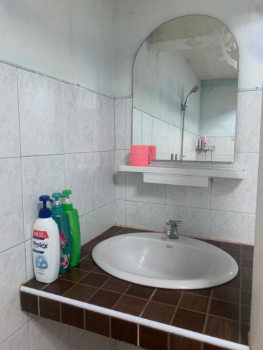 La salle de bains est pourvue d'un lavabo, d'un miroir et d'un détergent vert. dans l'établissement Baan Ja Da, à Ban Nai Khlong