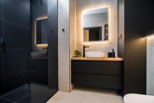 a bathroom with two sinks and a glass shower at Black Pearl Apartment starówka in Elblag