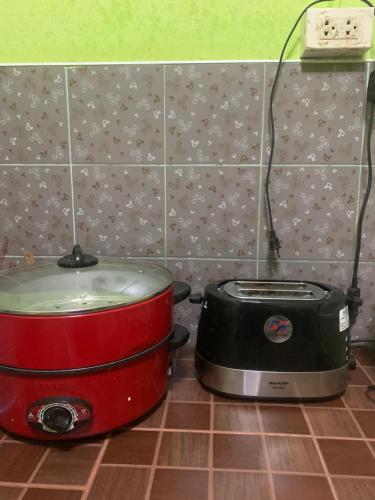 a slow cooker and toaster sitting on a kitchen floor at Baan Ja Da in Ban Nai Khlong