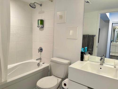 a white bathroom with a tub and a toilet and a sink at City Lake 2 Storey Condo in Toronto