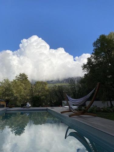 une chaise assise à côté d'une piscine avec des nuages dans le ciel dans l'établissement Villa Martine, à Nans-les-Pins