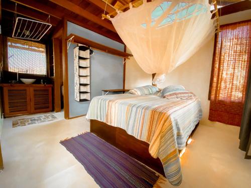 een slaapkamer met een bed in een kamer met ramen bij CASA Ecológica Paraty in Paraty