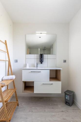 une pièce blanche avec un lavabo et un miroir dans l'établissement Maison Piscine Zénith d'auvergne Clermont Sud, à La Roche-Blanche