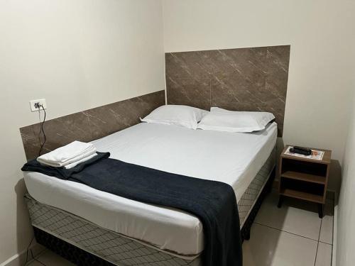 um quarto com uma cama grande com lençóis brancos e almofadas em Hostel Quartos com banheiro individual perto do Aeroporto em Guarulhos