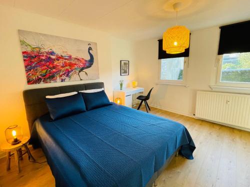 a bedroom with a blue bed and a painting on the wall at "LA MAIN D'OR " avec espaces Sauna et salle de Sport in Spa