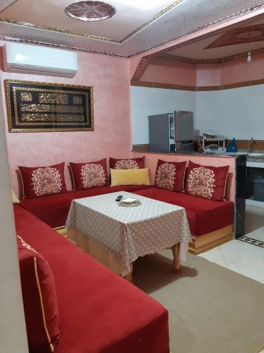een woonkamer met een rode bank en een tafel bij دوار السخينات in Es Skhinat