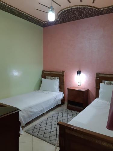 duas camas num quarto com paredes cor-de-rosa e duas mesas em دوار السخينات em Es Skhinat