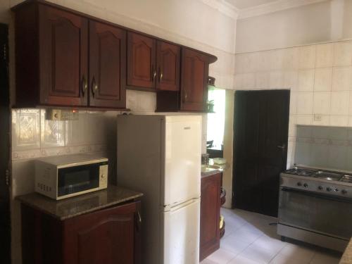 cocina con armarios de madera y nevera blanca en Tatys homestay, en Dar es Salaam