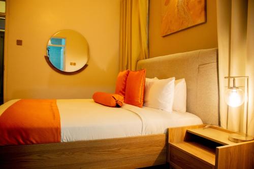 a bedroom with a bed with orange pillows and a mirror at Blueberry Villas in Eldoret