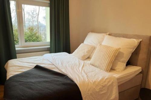 ein Bett mit weißen Kissen und ein Fenster in einem Zimmer in der Unterkunft Top sanierte Wohnung nahe Winterberg Klinikum in Saarbrücken