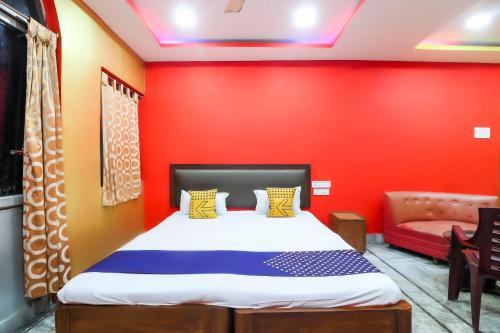a bedroom with a bed and a red wall at Hotel O Bright in Jamshedpur