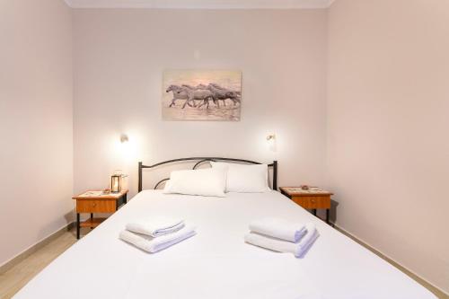a bedroom with a large white bed with two tables at Maria Rooms in Polychrono