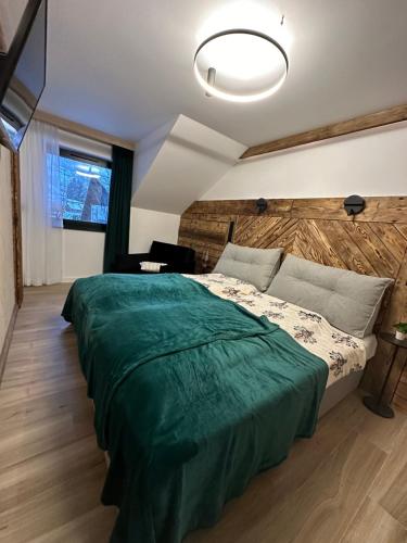 a bedroom with a large bed with a green blanket at Narciarska6A Apartamenty in Szczyrk
