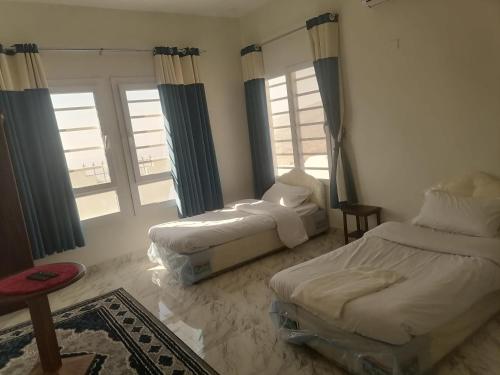 1 Schlafzimmer mit 2 Betten und 2 Fenstern in der Unterkunft Jabal Shams bayt kawakib in Misfāh