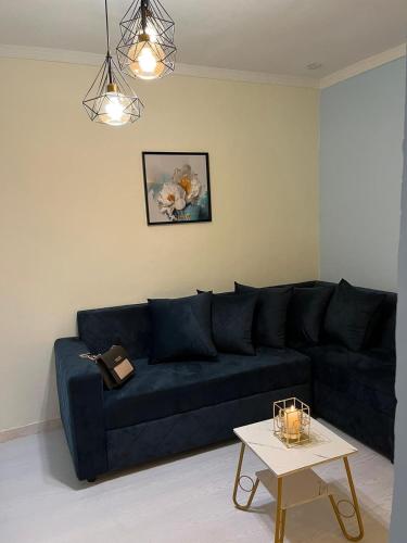 ein blaues Sofa im Wohnzimmer mit einem Tisch in der Unterkunft Chez Astrid in Jaunde