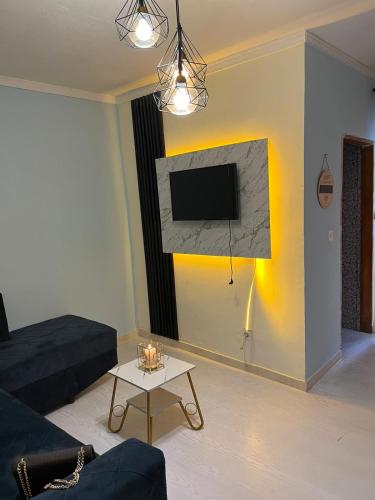ein Wohnzimmer mit einem Sofa und einem TV an der Wand in der Unterkunft Chez Astrid in Jaunde