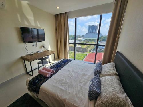 a hotel room with a bed and a desk and a television at Kozi Square comfort Studio Home 2D in Kuching