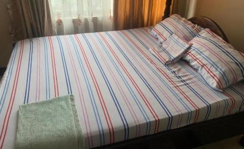 a bed with a striped sheet and a pillow at Tatys homestay in Dar es Salaam