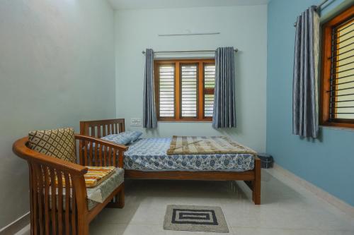 a bedroom with a bed and a chair and a window at Padma Bliss Guest House in Mangalore