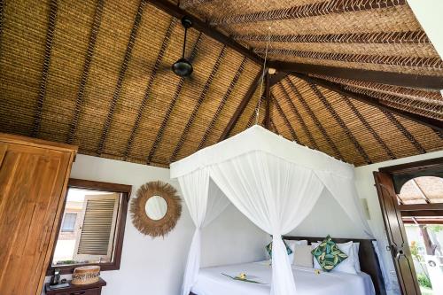 a bedroom with a canopy bed in a straw roof at Pondok Santi Estate in Gili Trawangan