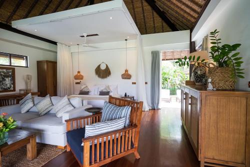 a living room with a white couch and chairs at Pondok Santi Estate in Gili Trawangan