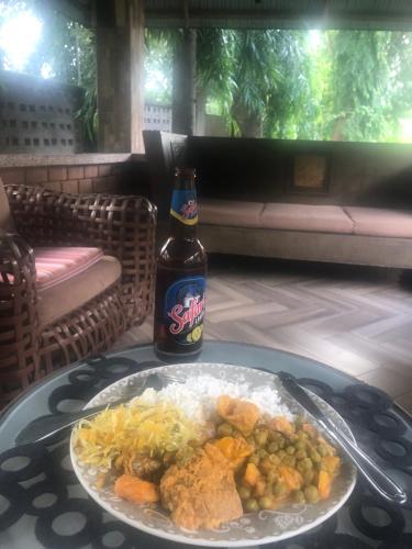 a table with a plate of food and a bottle of beer at Tatys homestay in Dar es Salaam