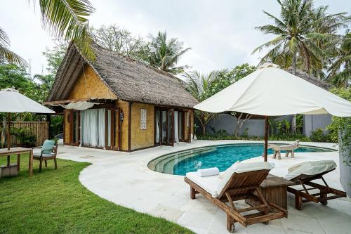 a villa with a pool and chairs and an umbrella at Pondok Santi Estate in Gili Trawangan